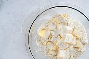 Cubes cold butter  in a glass bowl with all-purpose flour in preparation to make puff pastry.