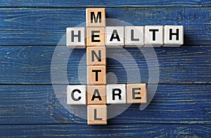 Cubes composed words MENTAL HEALTH CARE on color wooden table
