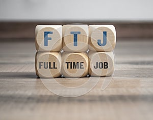 Cubes or dice with acronym FTJ for Full Time Job on wooden background