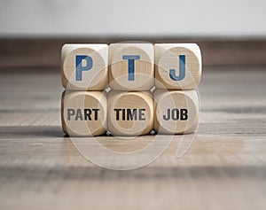 Cubes or dice with acronym PTJ for Part Time Job on wooden background