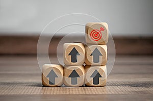 Cubes and dice with arrow and bow metaphor for goal or target on wooden background