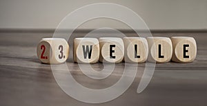 Cubes, dice or blocks with covid-19 corona virus and the german words for wave - welle on wooden background