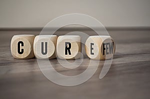 Cubes, dice or blocks with cure and curfew on wooden background