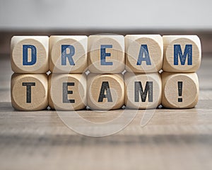 Cubes, dice or blocks with dreamteam or dream team on wooden background