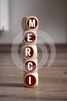 Cubes, dice or blocks with french word merci - thank you, thanks on wooden background
