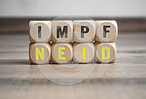 Cubes, dice or blocks with the german word for vaccination envy - Impfneid on wooden background