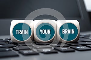 Cubes, dice or blocks on laptop keyboard with message train your brain