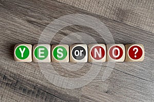 Cubes, dice or blocks showing the words YES or NO on wooden background