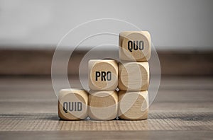 Cubes and dice with business message quid pro quo on wooden background