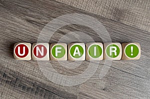 Cubes and dice with fair and unfair on wooden background