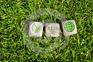 Cubes or dice in green grass with message plastic free