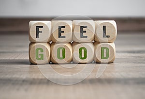 Cubes and dice with message feel good on wooden background