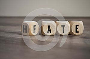 Cubes and dice with the opposite of hate and fate on wooden background