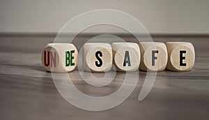 Cubes and dice with unsafe and be safe on wooden background