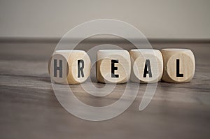 Cubes and dice with words heal and real on wooden background