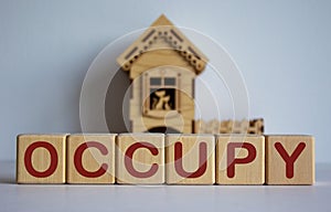 Cubes form the word `occupy` in front of a miniature house