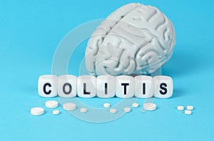 Cubes lie on the table among the pills and imitation of the brain. The text on the dice - COLITIS