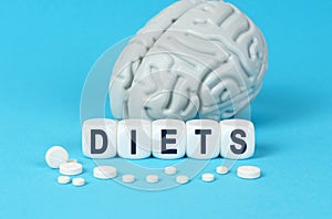Cubes lie on the table among the pills and imitation of the brain. The text on the dice - DIETS