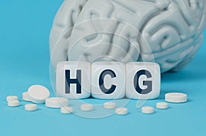 Cubes lie on the table among the pills and imitation of the brain. The text on the dice - HCG