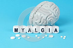 Cubes lie on the table among the pills and imitation of the brain. The text on the dice - MYALGIA