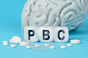 Cubes lie on the table among the pills and imitation of the brain. The text on the dice - PBC