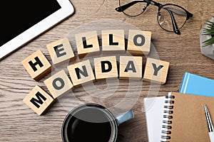 Cubes with message Hello Monday, office stationery and cup of coffee on wooden desk, flat lay