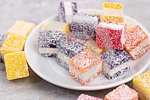 Cubes of multi-colored marmalade in powdered sugar on plate. The concept of baby sweets