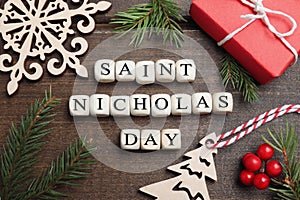 Cubes with phrase Saint Nicholas Day, gift box and festive decor on wooden table, flat lay photo