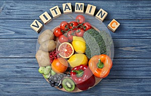 Cubes with phrase VITAMIN C and fresh products on wooden table, flat lay