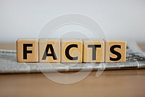 Cubes placed on a newspaper form the word `facts`. Beautiful wooden table. White background. Business concept. Copy space