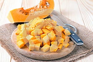 Cubes of pumpkin on cutting board and knife on wooden table