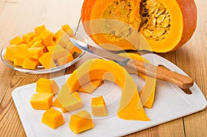 Cubes of pumpkin in plate, cutting board and knife