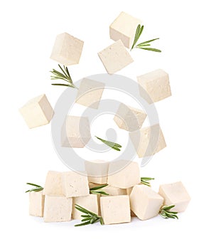 Cubes of raw tofu falling into pile on white background