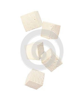 Cubes of raw tofu falling on white background