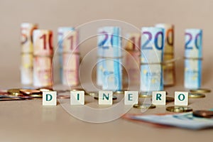 Cubes spelling Dinero in front of Spanish dinero bills and coins on the table