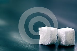 Cubes of sugar on a dark background. Unhealthy ingredients. Lump sugar