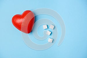 Cubes of sugar and red heart on a blue background