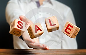 Cubes thrown by a man make up the word Sale. Big sale and high discounts on goods. Promotions and advertising, attracting