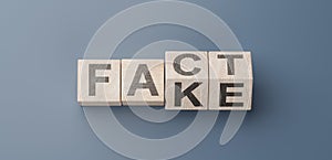 cubes turning message FACT to FAKE. Turned wooden cubes with words Fact vs Fake. Blue background. Business and Fact vs Fake