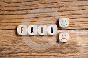Cubes with the word FAIR and decision between happy or sad smiley