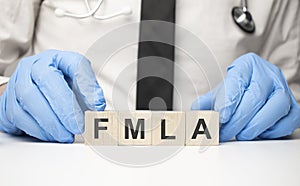 cubes with the word fmla on doctor's hand. Care concept photo