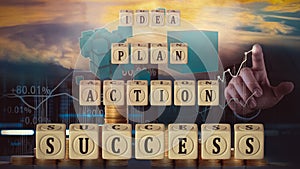 Cubes with the words `Idea`, `Plan`, `Action` and `Success` are arranged in steps against the background of a man`s hand,