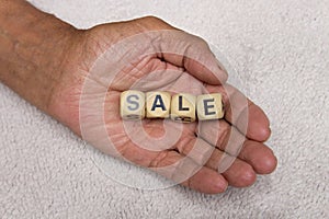 Cubes with the words SALE in the hands of an elderly person. The concept of sale