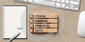 Cubes with the words STRENGTH, WEAKNESSES, OPPORTUNITIES and THREATS with notepad and keyboard - 3D rendered illustration