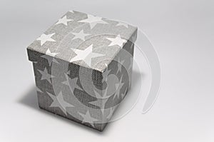 Cubic gray cardboard box decorated with white stars. Craft box