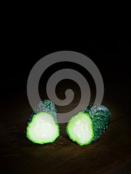 Cucumber cut in half on dark board