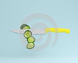 Cucumber cut into pieces with stainless kitchen knives on blue p