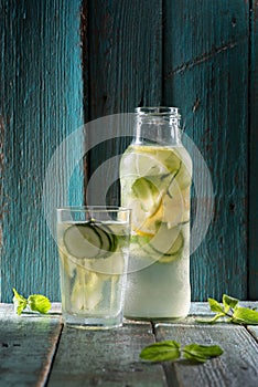 Cucumber lemon mint lemonade in glass bottle on dark old painted background