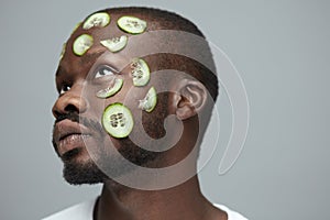 Cucumber Mask. Skin Care For Man`s Beauty Treatment. African Male Model Doing Facecare Routine. photo