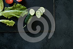 Cucumber and salad leaves on dark slate texture photo